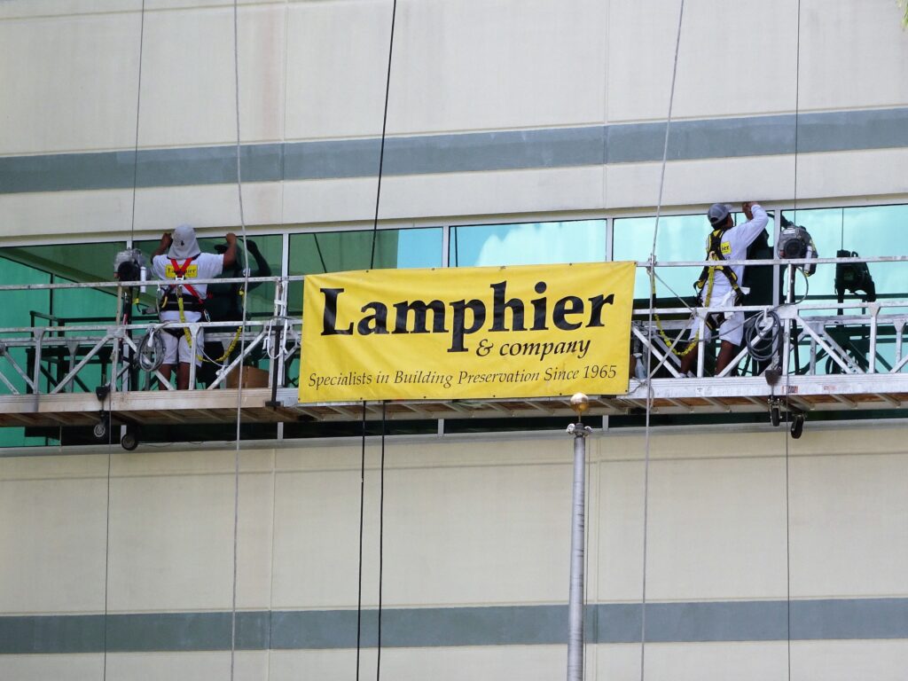Lamphier & Company banner displayed on a lift at a job site, promoting commercial services